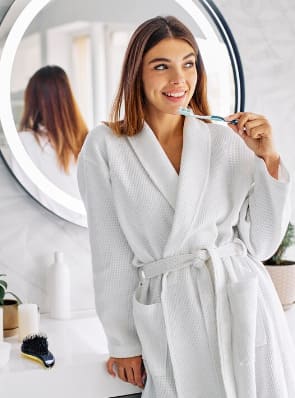 A white bathrobe worn women holding brush showing confident